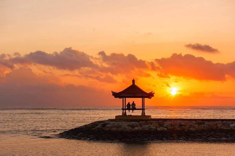 Bình minh trên bãi biển Sanur, ánh sáng vàng nhạt chiếu, biển phẳng lặng như gương