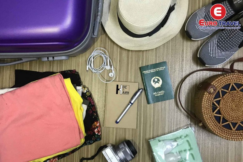Checklist hành lý du lịch Bali xếp gọn trên bàn: kem chống nắng, sarong, dép sandal, hộ chiếu