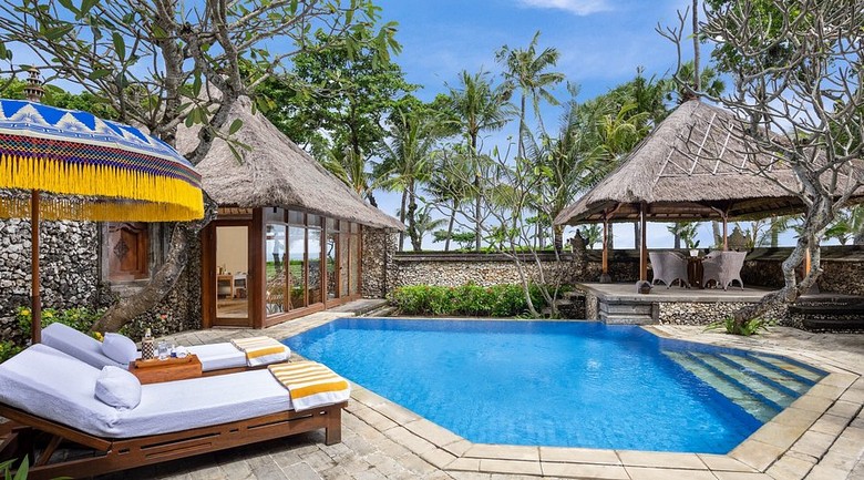 Hồ bơi villa Bali view vườn nhiệt đới với ghế tắm nắng và dù che