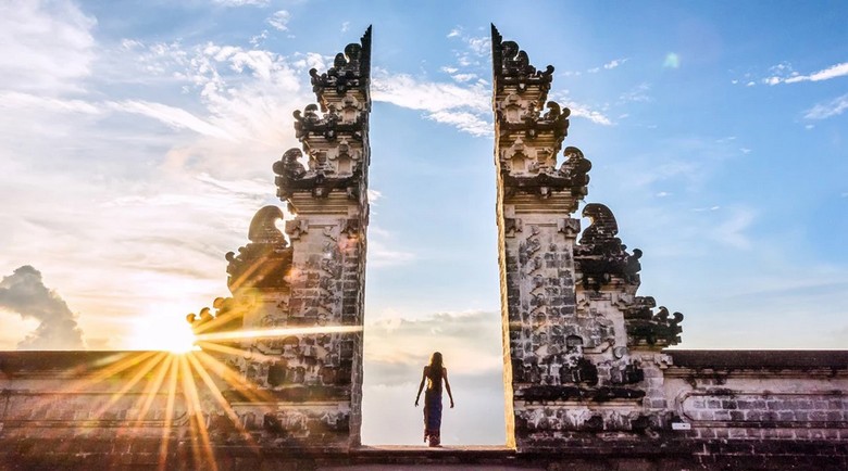 Khách nữ đi bộ qua cổng đền Lempuyang với cảnh núi lửa Agung phía sau