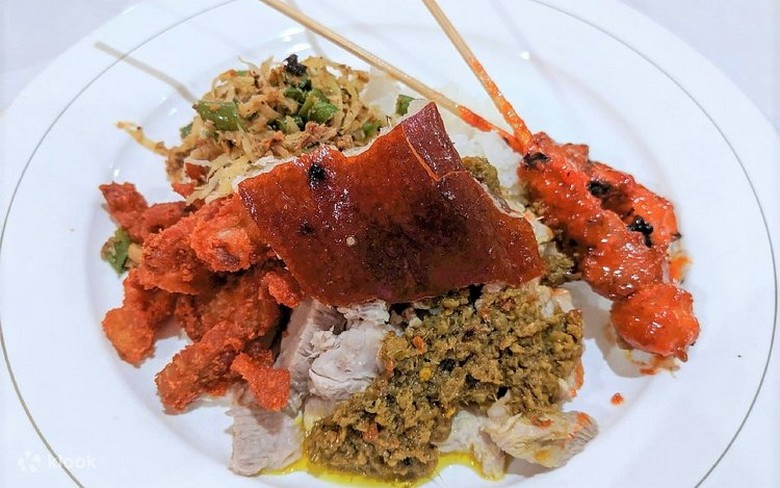 Đĩa Babi Guling nhìn từ trên xuống với da giòn vàng rộm, lawar xanh và cơm trắng tại warung Denpasar