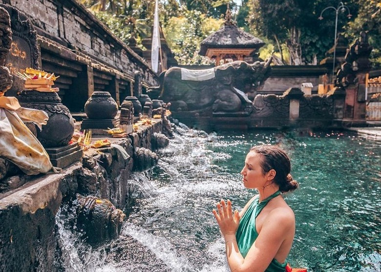 Người tham gia nghi lễ melukat đứng cầu nguyện dưới vòi nước