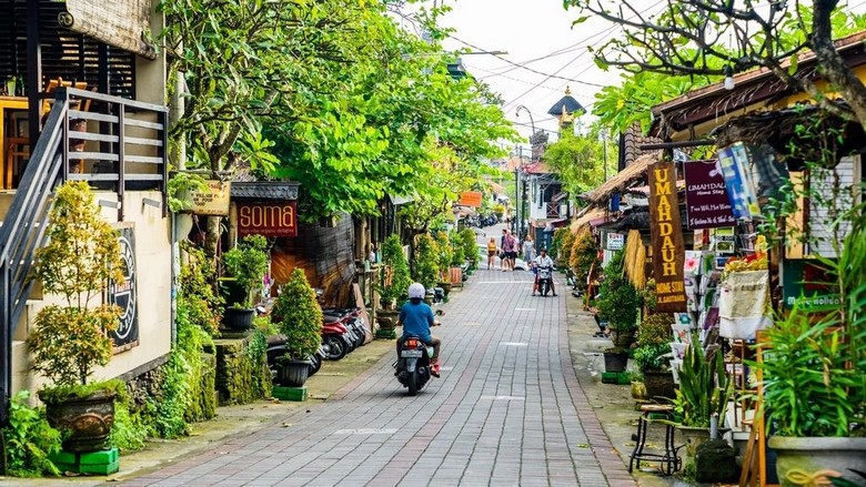 Con phố nhỏ ở trung tâm Ubud với hàng quán hai bên, cây xanh và bầu trời trong xanh
